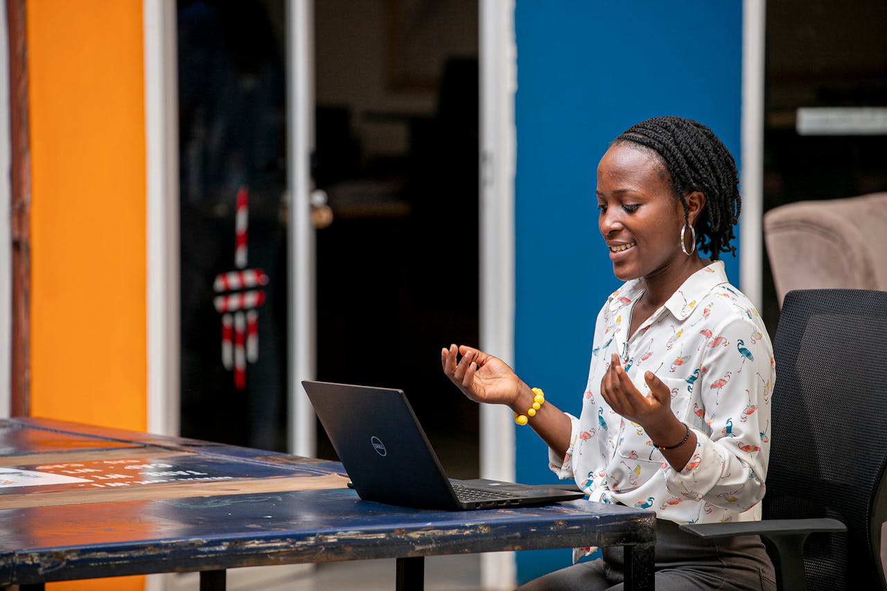 Smiling African woman with dreadlocks having an online video call in a colorful office.