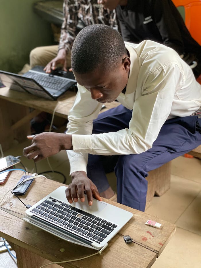 Young man deeply concentrating over laptop, learning in Nigerian setting.