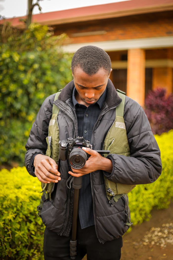 African male photographer setting up camera outdoors in Ruhengeri, Rwanda.